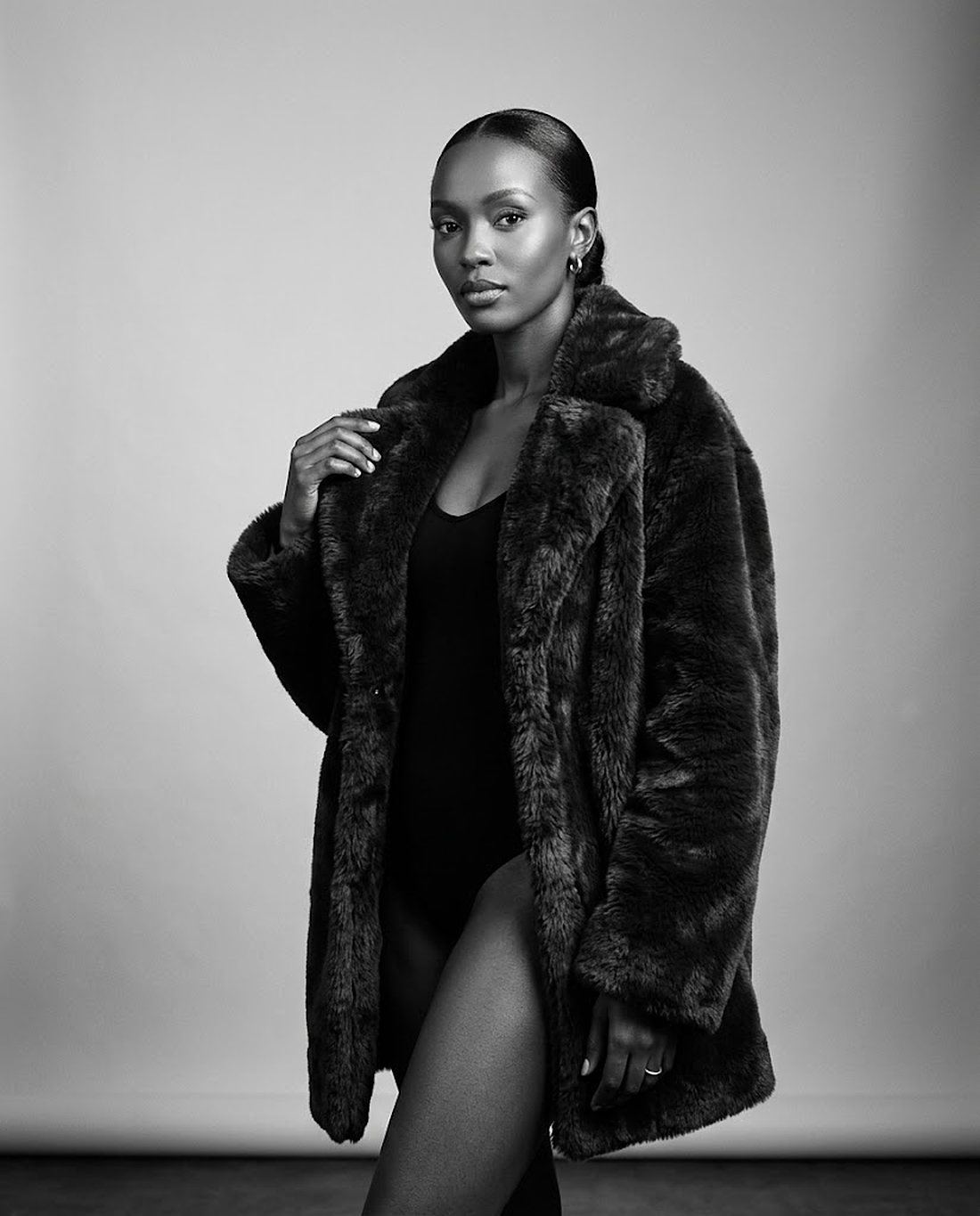 Black and white editorial portrait of a woman in a fur coat