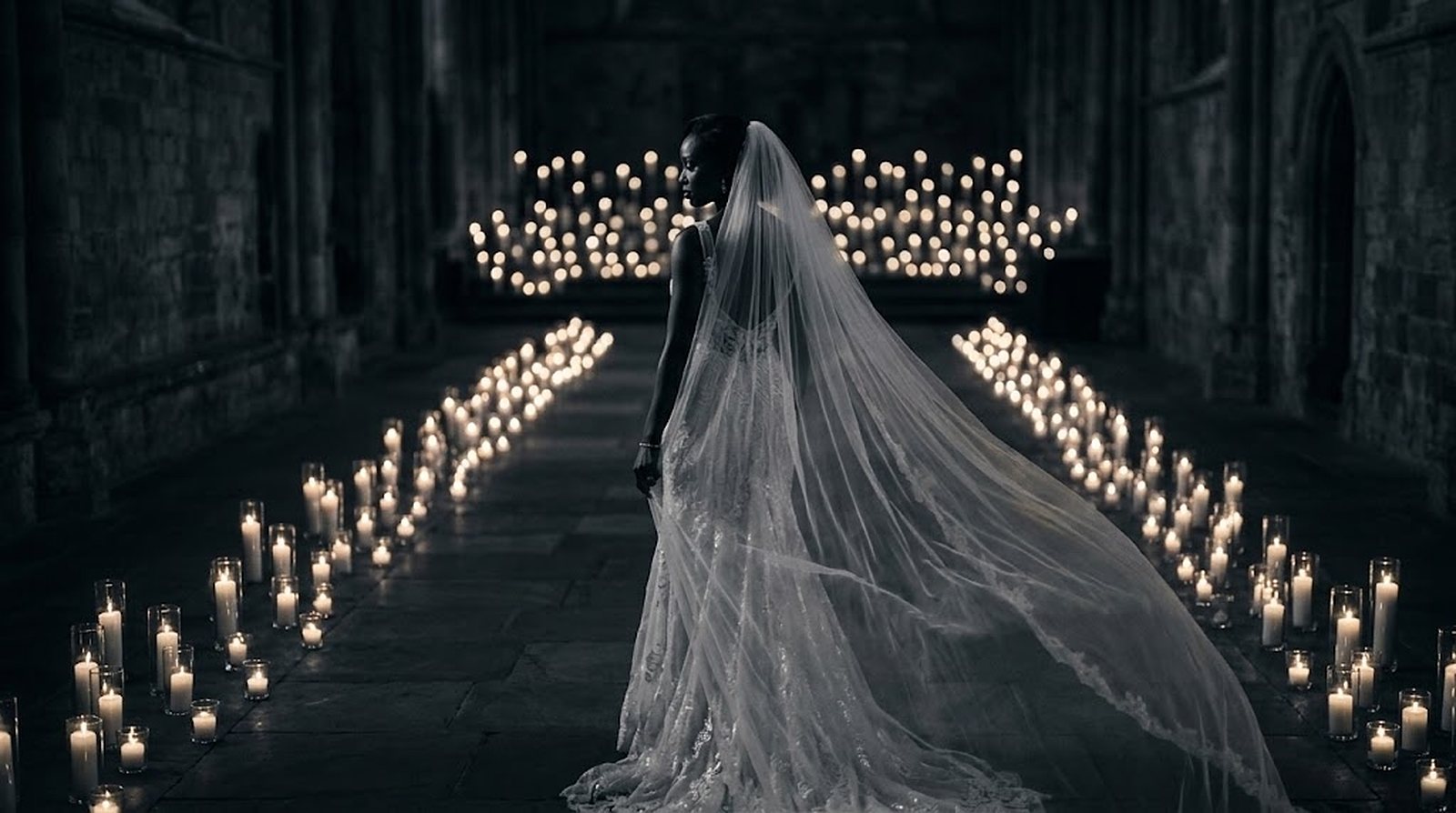 Film still of a bride walking down a candle-lit aisle